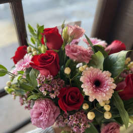 Bouquet of red and pink roses with pink daisies in a hand-held wrap