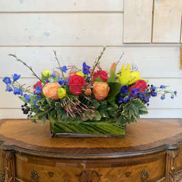 Colorful mixed flower arrangement in a rectangular glass vase