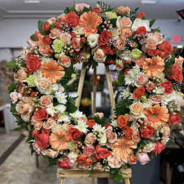 Large floral wreath with roses, gerbera daisies, and small filler flowers