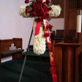 Red roses and white hydrangeas arranged on a standing cross