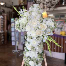 White floral cross arrangement on an easel