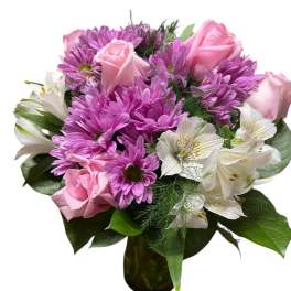 Pink roses and purple daisies in a glass vase with white alstroemeria