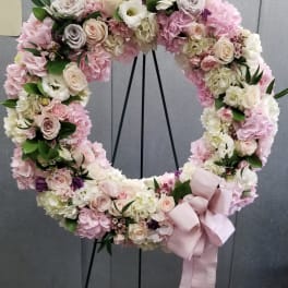 Pastel floral wreath with roses, hydrangeas, and a pink ribbon bow