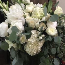 White floral arrangement with roses, hydrangeas, and greenery in a vase