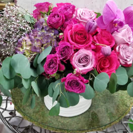 Pink and purple rose arrangement with orchids in a white vase
