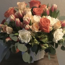 Bouquet of coral and white roses with pink tulips in a wrapped container