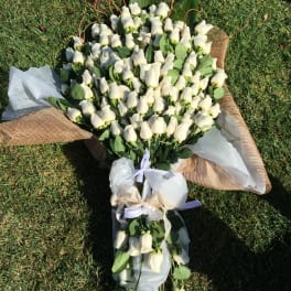 Large bouquet of white roses wrapped in white and burlap paper
