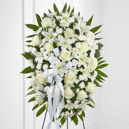 White floral standing spray with roses and lilies on an easel