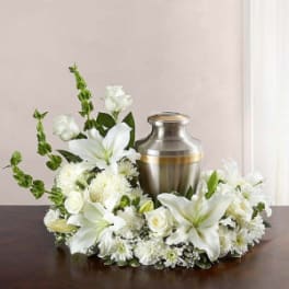 White floral wreath around a silver urn on a table
