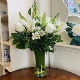 White lilies and roses in a green glass vase
