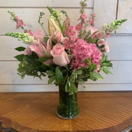 Pink floral arrangement in a clear glass vase with lilies and roses
