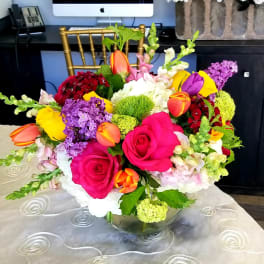 Bright mixed bouquet of roses, tulips, and hydrangea in a glass vase