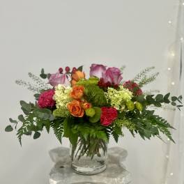 Mixed pink, orange, and green flower arrangement in a clear glass vase