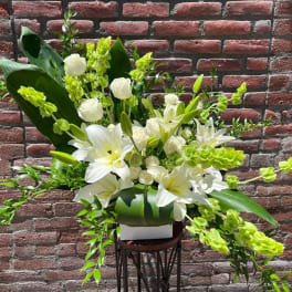 White lilies and roses arranged with bright green accents in a white vase