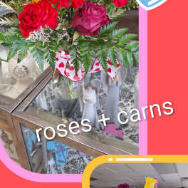 Mixed bouquet of roses and carnations in a glass vase with a heart ribbon.