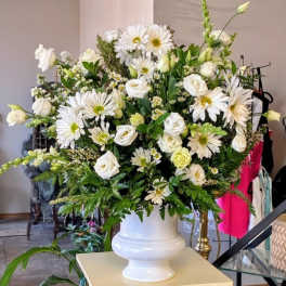 Large white floral arrangement in a white urn vase