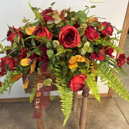 Large arrangement of red roses and orange flowers with fern foliage on a stand