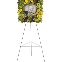 Standing floral photo tribute on an easel with a portrait in the center