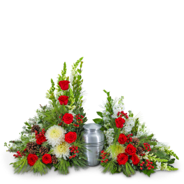 Sympathy urn arrangement with red roses, white flowers, and pinecones around a silver urn
