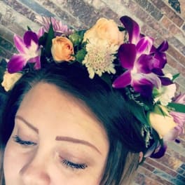 Woman wearing a floral crown with purple orchids and peach roses