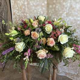 Large floral arrangement with cream and blush roses, lilies, and pink accents