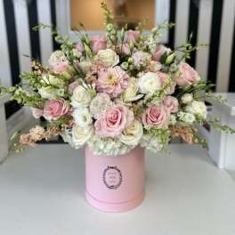 Pink and white roses arranged in a pink hat box