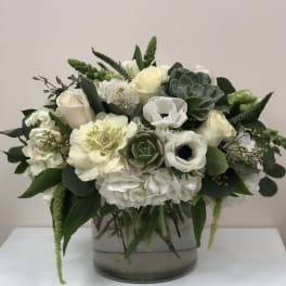 White and pale green floral arrangement in a clear glass vase