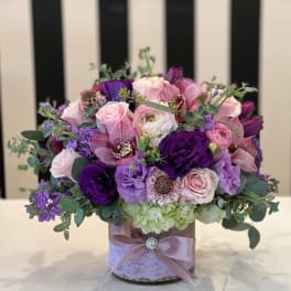 Pink and purple bouquet in a decorated round box