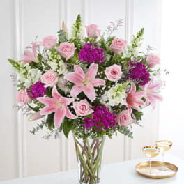 Pink lilies and roses arranged in a clear glass vase