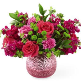 Pink and magenta flower arrangement in a textured glass vase