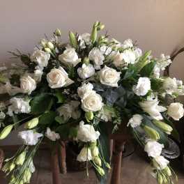 Large white floral arrangement with roses and lilies in a basket
