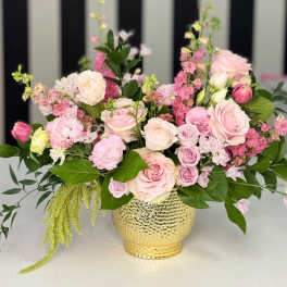 Pink and white floral arrangement in a gold vase