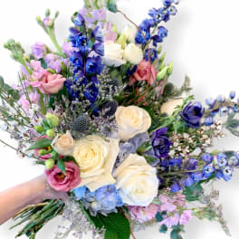 Handheld bouquet of white, pink, and blue flowers with long stems