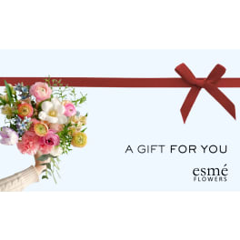 Handheld bouquet of mixed pastel flowers with a red ribbon bow