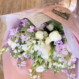Bouquet of white roses and lavender flowers wrapped in pink paper