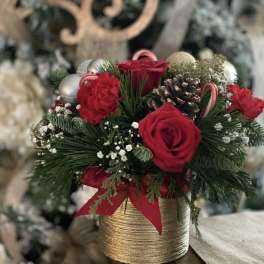 Red roses and carnations in a gold vase with pinecones and ornaments