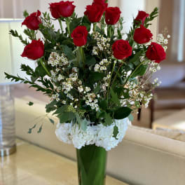 Red roses and white hydrangeas in a tall glass vase