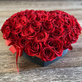 Heart-shaped box filled with red roses and a red ribbon