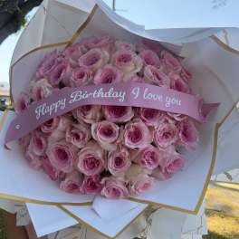 Bouquet of pink roses wrapped in white paper with a birthday ribbon