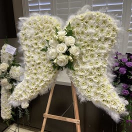 White floral heart-shaped standing spray with roses and daisies on an easel