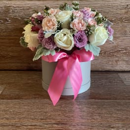 Pink and white rose arrangement in a round box with a pink ribbon