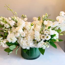 White floral arrangement in a green glass vase