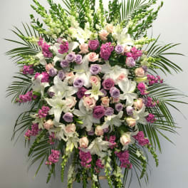 Standing floral spray with white lilies, pink and lavender roses, and magenta accents