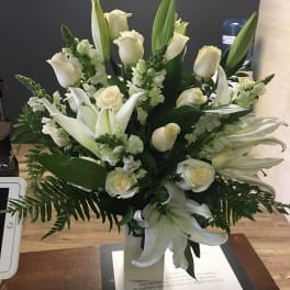 White roses and lilies arranged in a vase with greenery