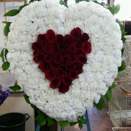 Heart-shaped floral tribute with red roses and white flowers
