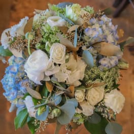 Bouquet of white and pale blue flowers with eucalyptus and gold-toned foliage