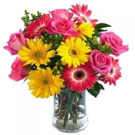 Pink roses and yellow gerbera daisies in a clear glass vase