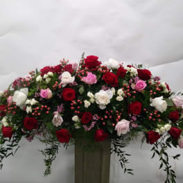 Large arrangement of red, white, and pink roses in a tall vase