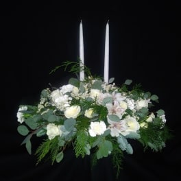 White floral arrangement with two tall white candles