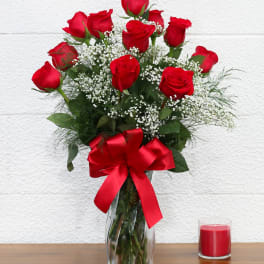 Red roses in a glass vase with a red ribbon and candle